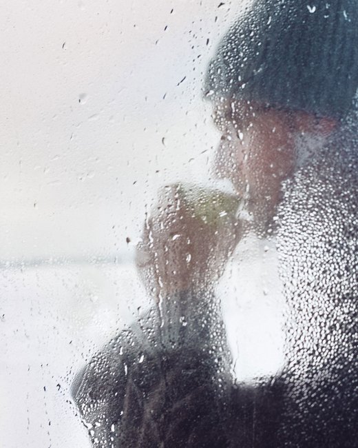 Finlande, hiver, homme buvant une boisson chaude derrière une vitre embuée