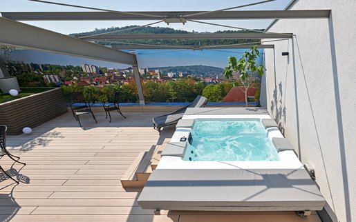 Détente dans le jacuzzi sur la terrasse : le jacuzzi installé par SSF.Pools by KLAFS dispose de différentes buses de massage, d'un massage à air et de lumière.